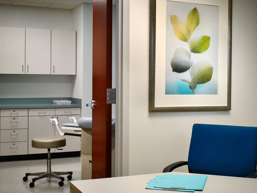 view into doctor's office exam room with a painting of bright blue and green leaves on the wall