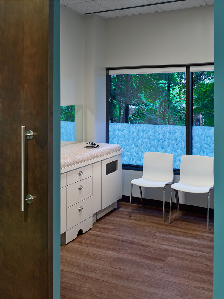 a waiting room with two white chairs and a large window