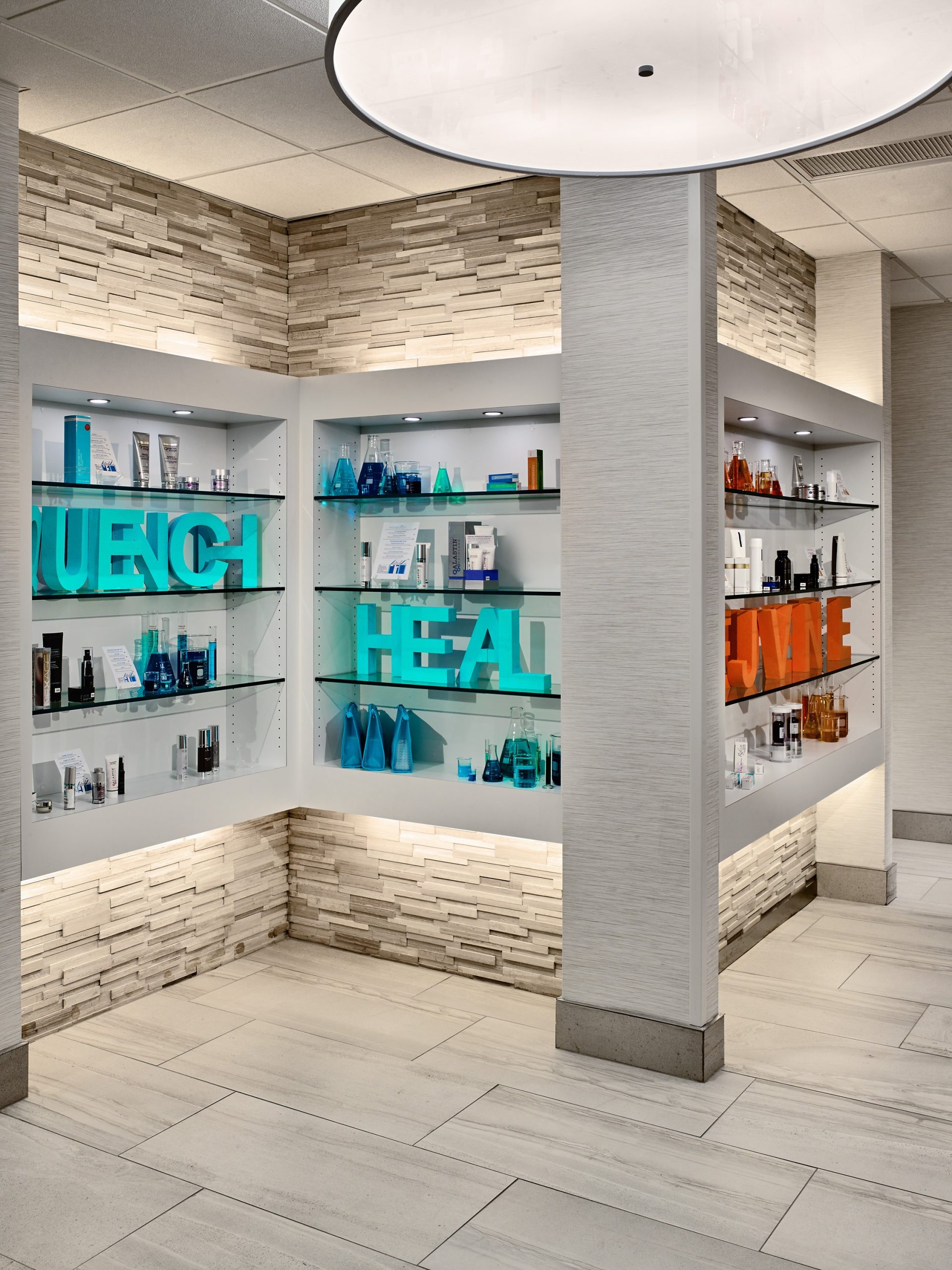 backlit product wall inside of Premier Cosmetic and Laser Surgery with shelf display words Quench and Heal
