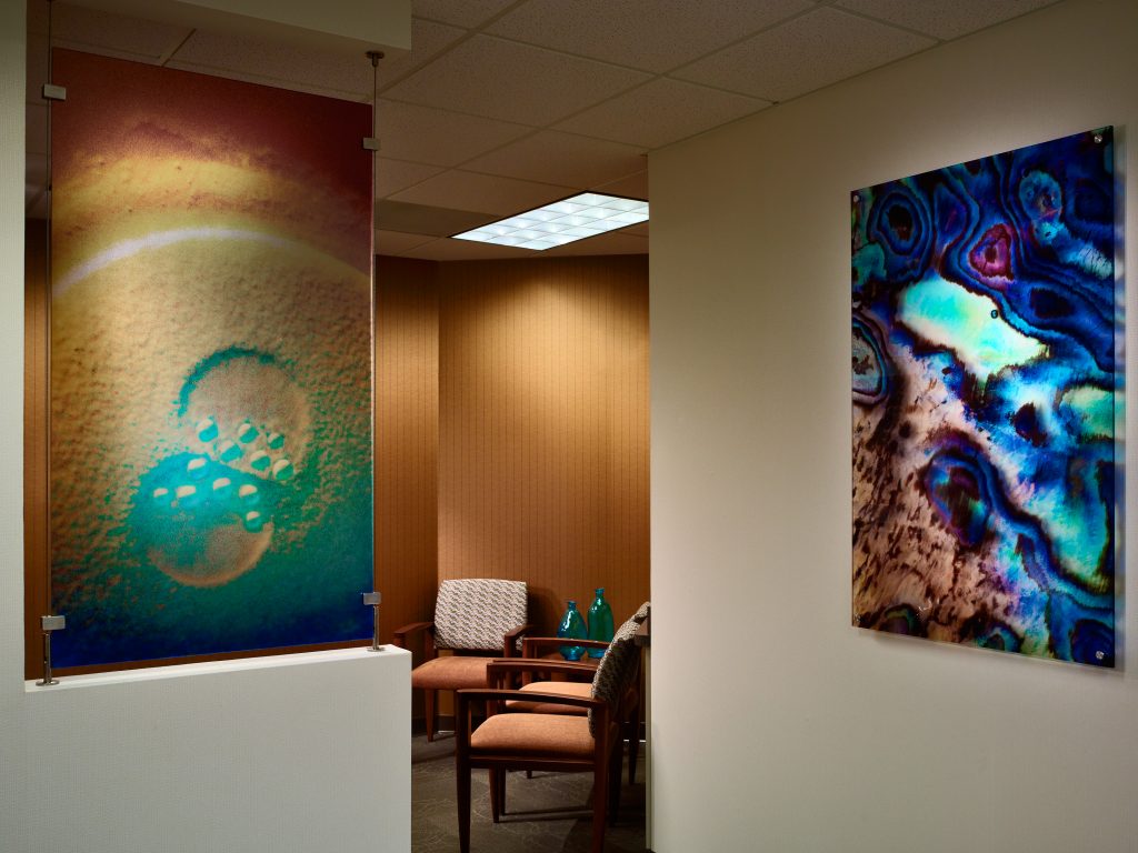 corner of a waiting room with warm wood walls and abstract paintings on the walls