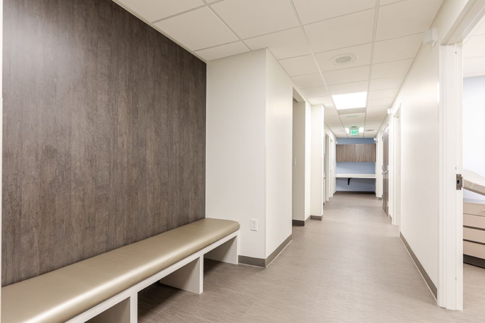 Comprehensive Women's OBGYN hallway with wood accent wall and seating area