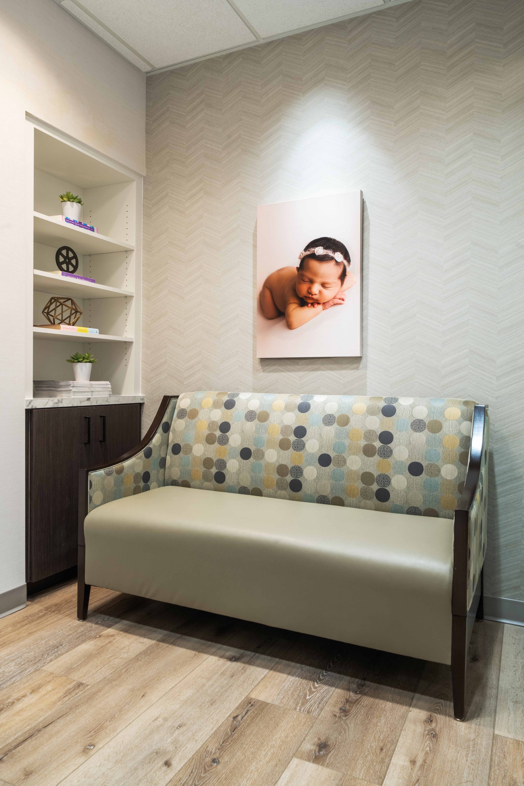 OBGYN office waiting room with a couch and hanging canvas photo of a baby girl with a flower crown