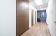 a long hallway with sleek wooden cabinets and an abstract wall painting