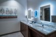 a bathroom with granite countertops, backlit mirrors and wall fixtures